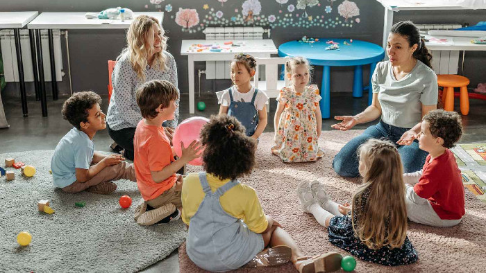 Crianças felizes em uma roda de conversa na escola, demonstrando interação social.