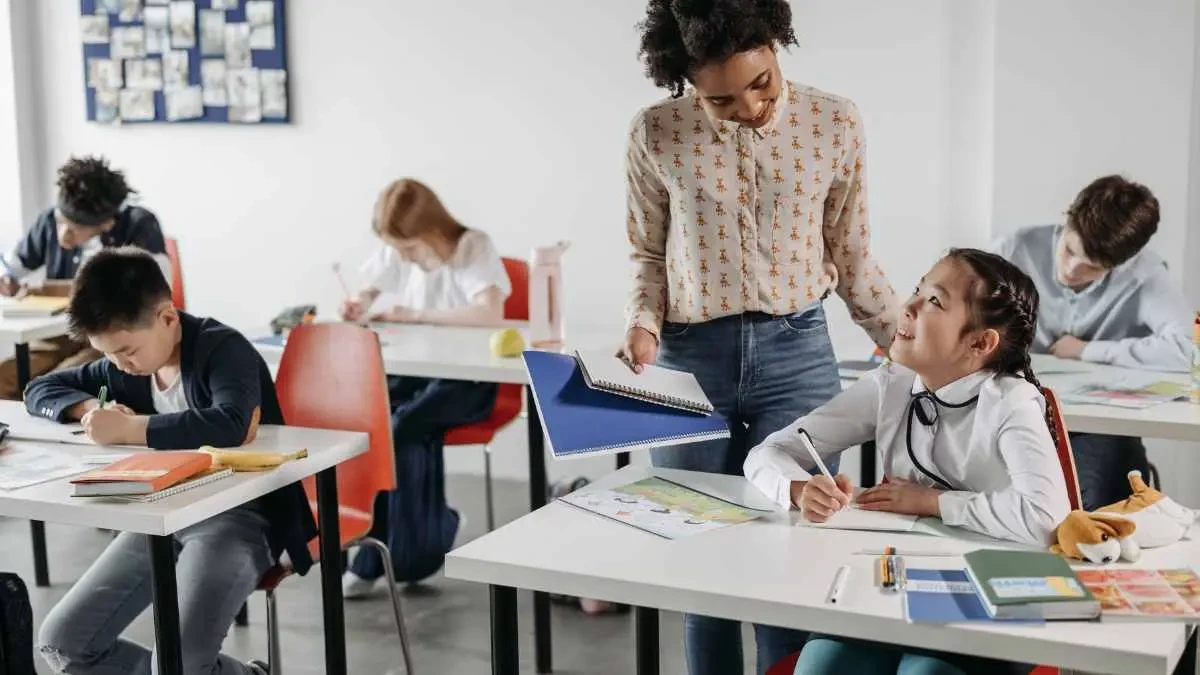 Professora auxiliando aluno em atividade escolar, ilustrando a união entre alfabetização e letramento na prática pedagógica.