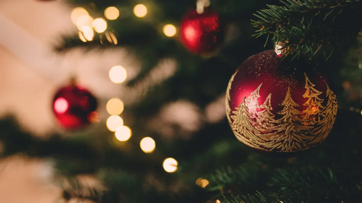 Menina sorrindo enquanto faz atividades natalinas para educação infantil, como pintar um enfeite de Papai Noel.